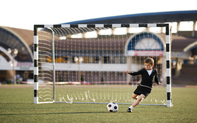 photo of little boy plays football on stadium